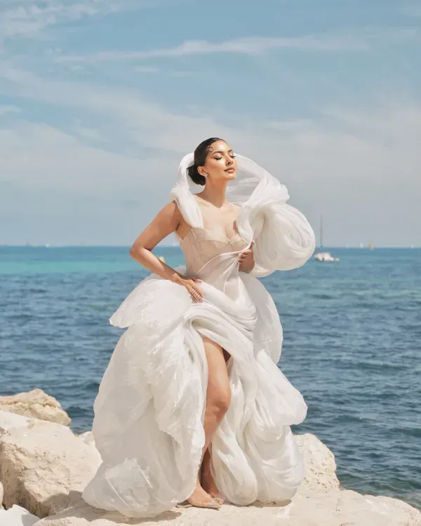 Shooting éditorial en bord de mer — robe couture en organza, chignon lissé et maquillage lumineux
