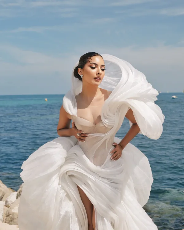 Shooting bord de mer Cannes, robe blanche sculptée et maquillage glamour soirée sur rochers Méditerranée