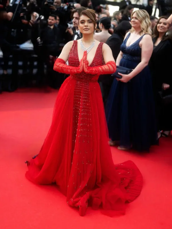 Gestes expressifs sur tapis rouge Cannes en robe rouge scintillante et gants, maquillage Sublimia