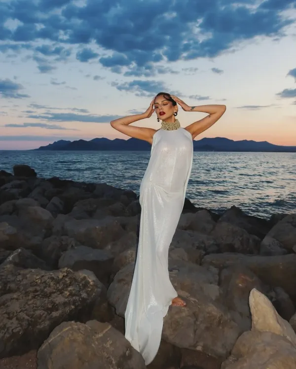 Portrait sur rochers Cannes avec collier doré et robe pailletée argentée, maquillage soirée Sublimia