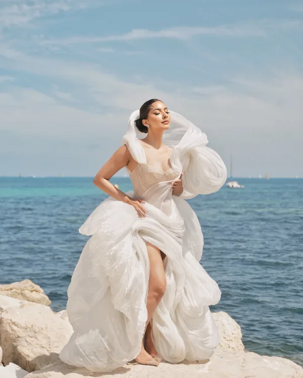 Pose artistique sur rochers Cannes, maquillage glamour et robe blanche sculptée au bord de la Méditerranée