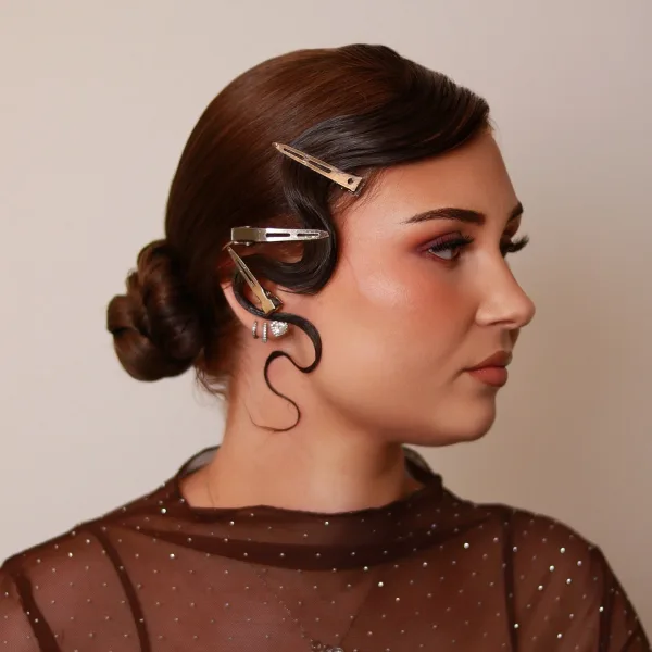 Chignon rétro sculpté avec épingles dorées et boucle S noire, coiffure événement Sublimia Toulouse